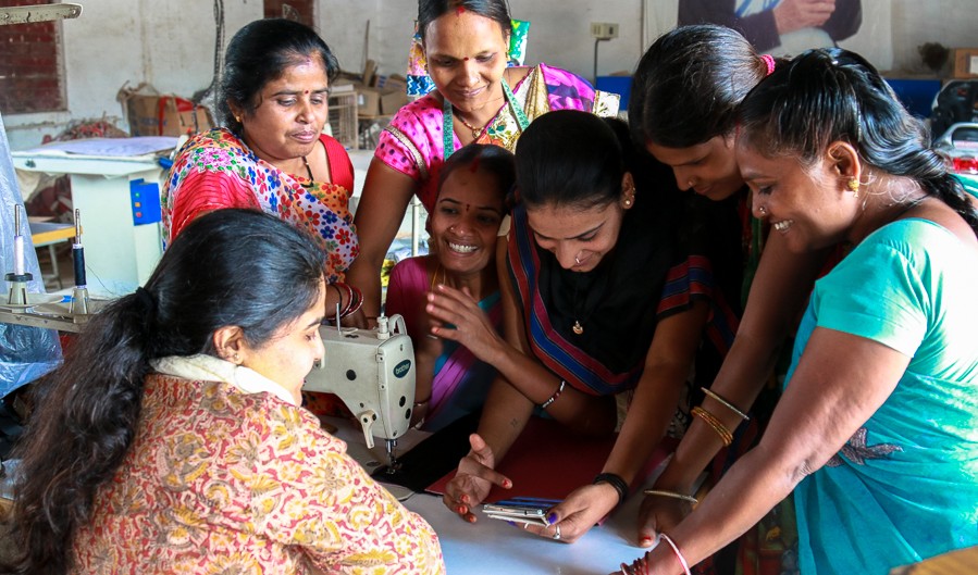 Women huddled together, looking at information on the phone together in MSK's vocational training center